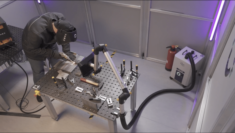 Man wearing laser welding PPE laser welds on a table inside a safety enclosure
